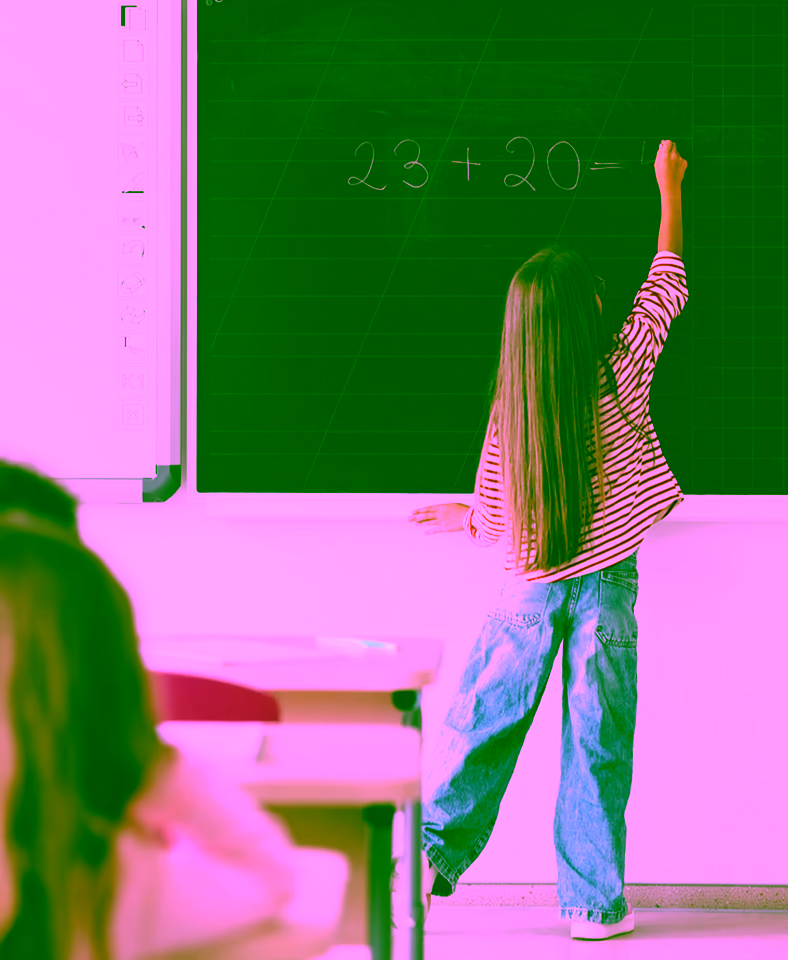 Schulmädchen schreibt eine Matheaufgabe an die Tafel im Klassenzimmer